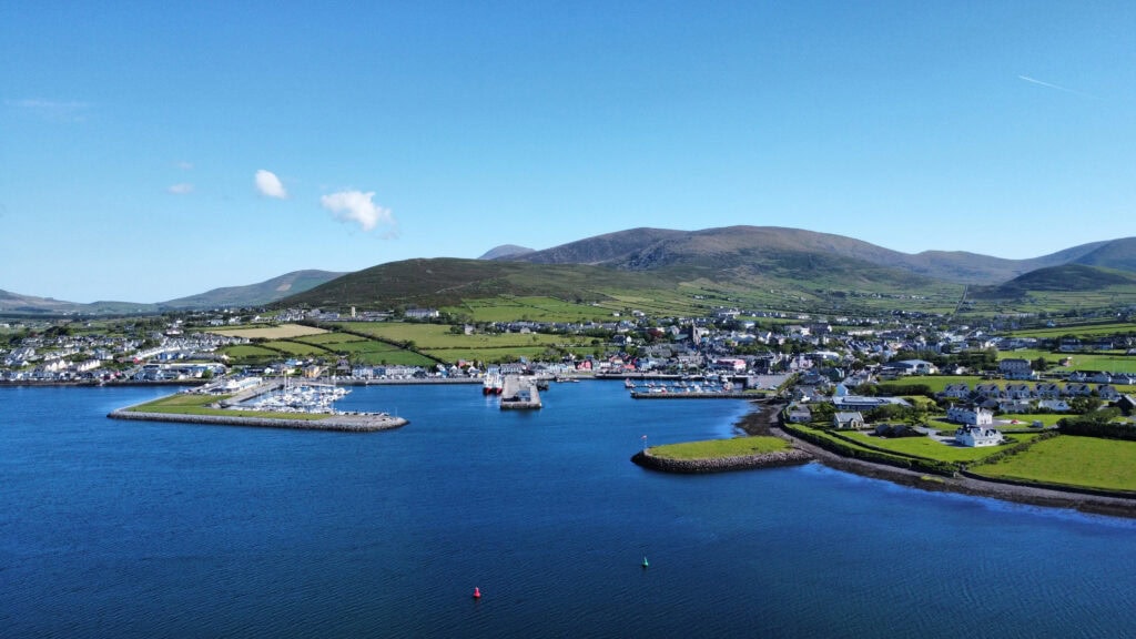 Aerial view of Dingle Pier and surrounding harbour, with town buildings and boats.