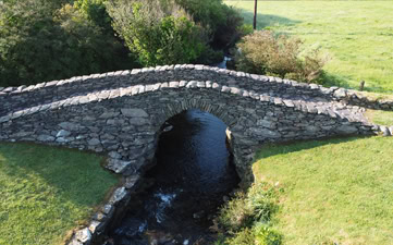 View beneath Garfinny Bridge spanning a scenic stream