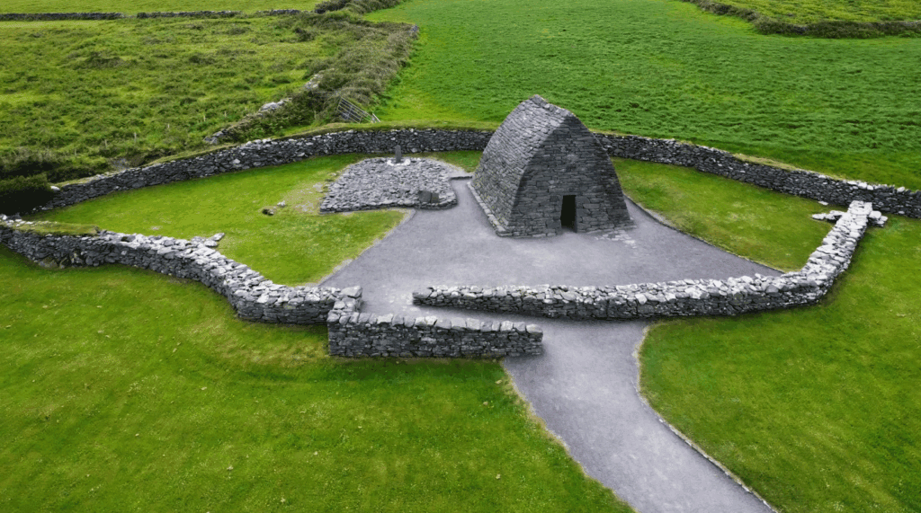 Aerial view of Gallarus Oratory with stone walls and the surrounding green landscape.