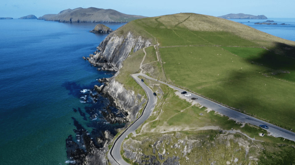 Aerial view of the cliffs above Coumeenoole Beach with Slea Head Drive winding beside the Atlantic and Blasket Islands offshore.