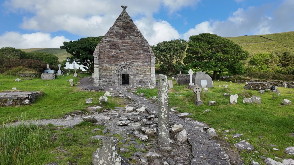 Front elevation of Kilmalkedar Church with its Romanesque doorway, surrounded by historic gravestones on the Dingle Peninsula, County Kerry.