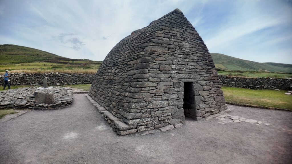Oblique view of Gallarus Oratory showing its corbelled stone roof, original doorway and precisely built dry-stone masonry on the Dingle Peninsula.