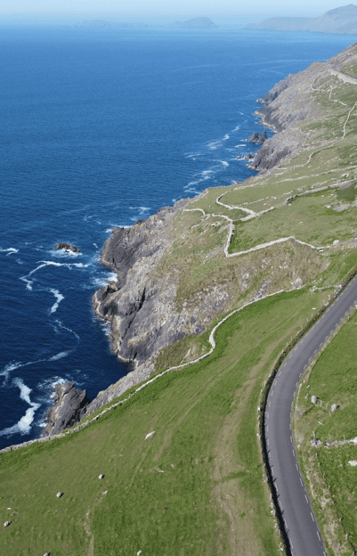 Aerial view of the rugged Atlantic cliffs and winding stone field walls surrounding Dún Beag Stone Fort on the Dingle Peninsula.