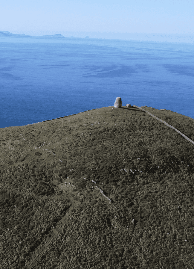 Aerial view of Eask Tower above the Atlantic Ocean with the distant Skellig Islands visible on the horizon off the Kerry coast.