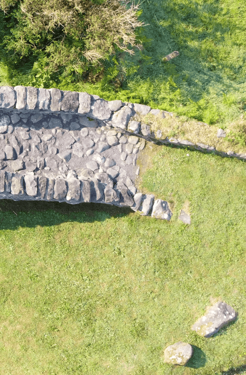 Close aerial view of the stone-paved deck and parapet wall at one end of Garfinny Bridge in County Kerry.