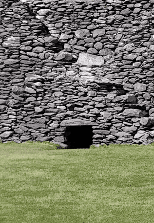 Small internal opening set into the massive dry-stone wall of Staigue Fort above the grass-covered enclosure.