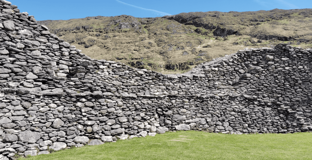 Interior dry-stone walls of Staigue Fort enclosing a grass-covered area beneath the surrounding Kerry hills.