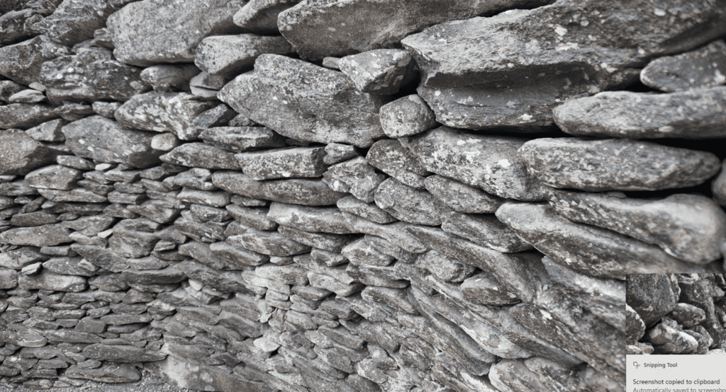 Close view of the carefully fitted dry-stone masonry forming the curved interior wall of a Fahan Clochán.