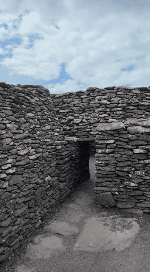 Narrow passage between substantial dry-stone walls leading to an entrance within the Fahan archaeological site.