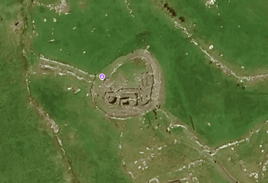 Aerial view of a stone-walled cashel containing several structures within the archaeological landscape at Fahan.