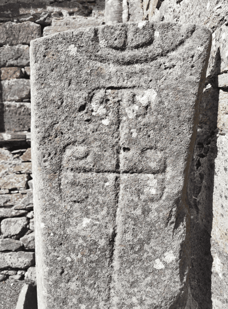 Carved cross on the face of the Kilmalkedar Ogham Stone, with additional weathered markings visible above the cross.