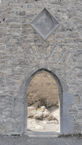 Pointed stone archway beneath a vaulted ceiling within the medieval ruins of Muckross Abbey in Killarney National Park.