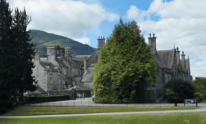 Muckross House seen through mature trees with mountains rising behind the nineteenth-century country house in Killarney National Park.