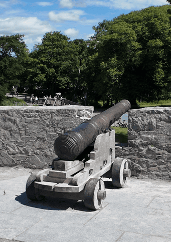 Historic iron cannon mounted on a wooden carriage within the stone defences of Ross Castle in Killarney National Park.