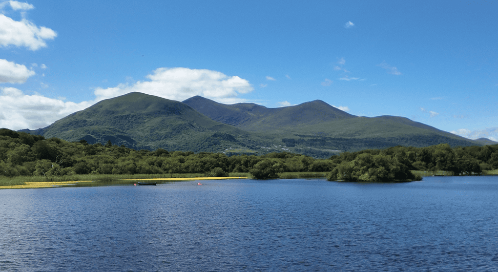 Lough Leane with wooded islands and the mountains of Killarney National Park rising beyond the water.