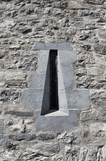 Narrow defensive opening set within the thick stone wall of Ross Castle, framed by precisely cut stone blocks.