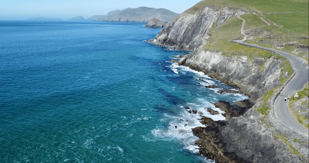 Aerial view along the rugged Slea Head coastline near Coumeenoole Beach, with steep cliffs, Atlantic Ocean and offshore islands.