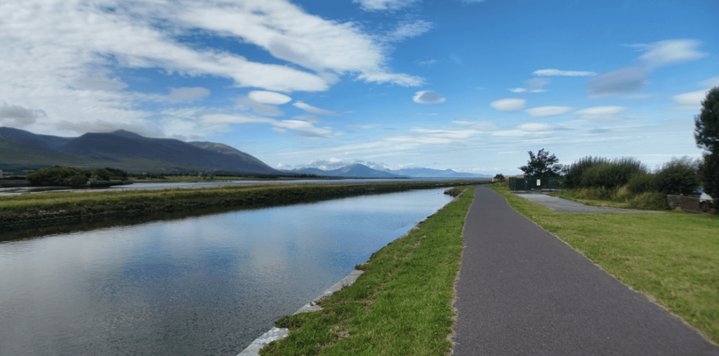 Tralee Ship Canal with a paved waterside path and the Slieve Mish Mountains rising across the landscape.