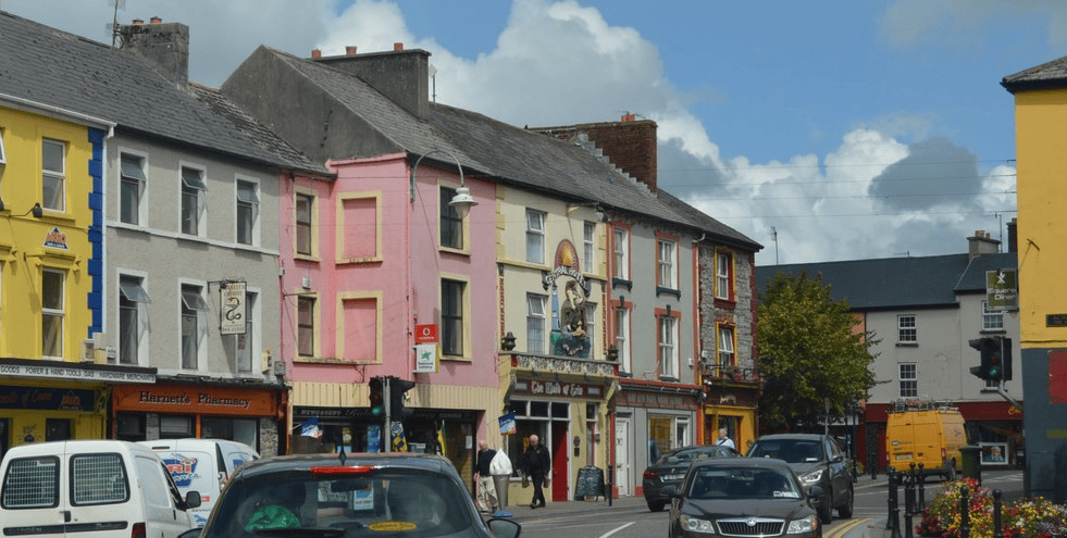 Colourful traditional shopfronts and upper-storey buildings lining a street in the centre of Listowel, County Kerry.