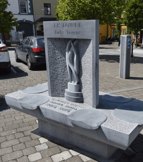 Listowel Tidy Towns stone monument with a carved flame design in a public square in Listowel, County Kerry.