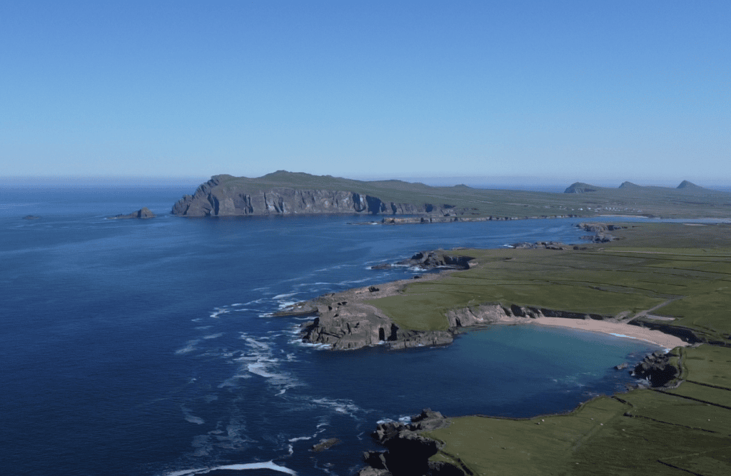 Aerial view across Clogher Head towards Ceann Sibéal, showing Atlantic cliffs, rocky coves, fields and offshore waters.