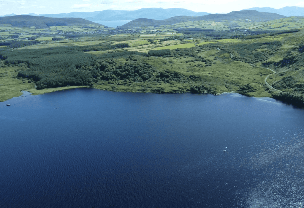 View across Annascaul Lake towards farmland and mountains on the Dingle Peninsula.